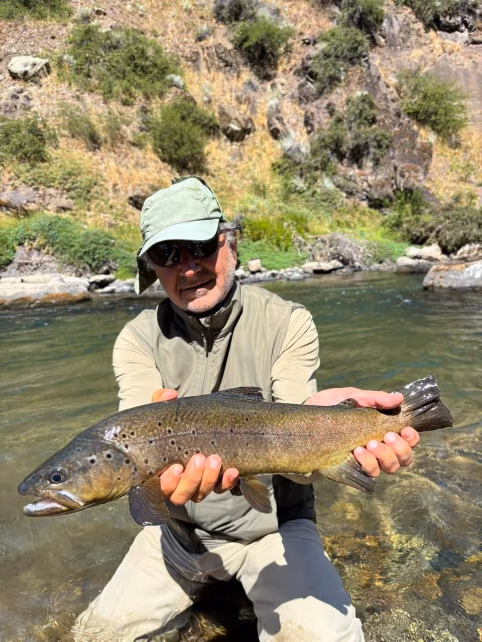 An angler with a brown trout, wading a rocky river near Coyhaique, Chilean Patagonia