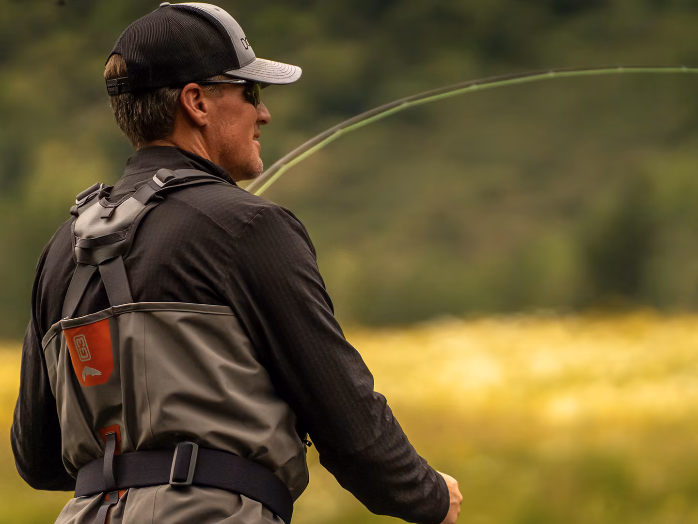 Angler wearing waders and a fly fishing chest pack casting a rod in Patagonia