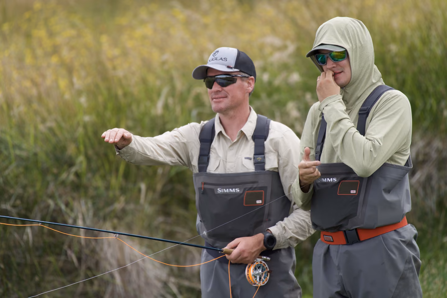 Two anglers on a creek in Chilean Patagonia, one pointing out the water to fish