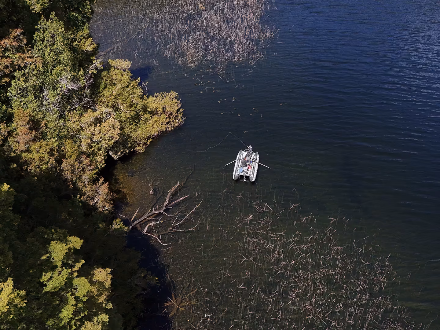 A cataraft fishing the weedy shoreline of Lago Zenteno, near Coyhaique, seen from above